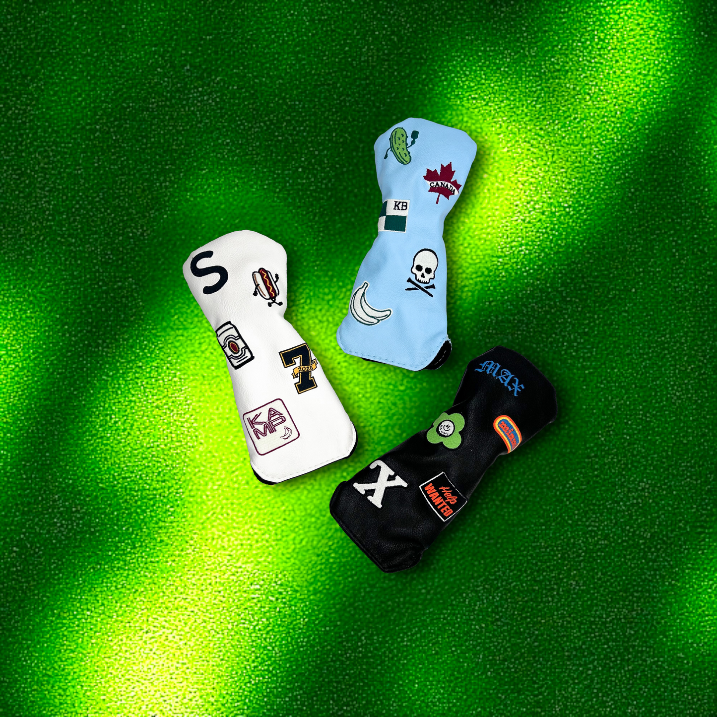 Three hybrid golf club head covers with custom patches laying on green turf