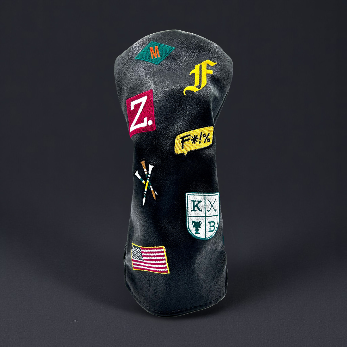 Black golf club driver head cover with custom patches on black backdrop