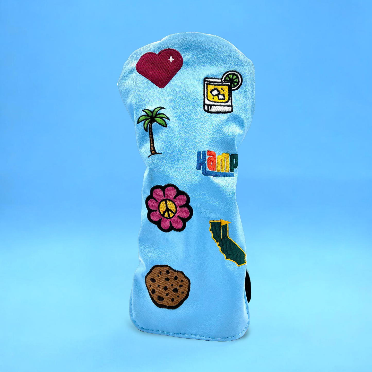 Blue golf club driver head cover with custom patches on blue backdrop