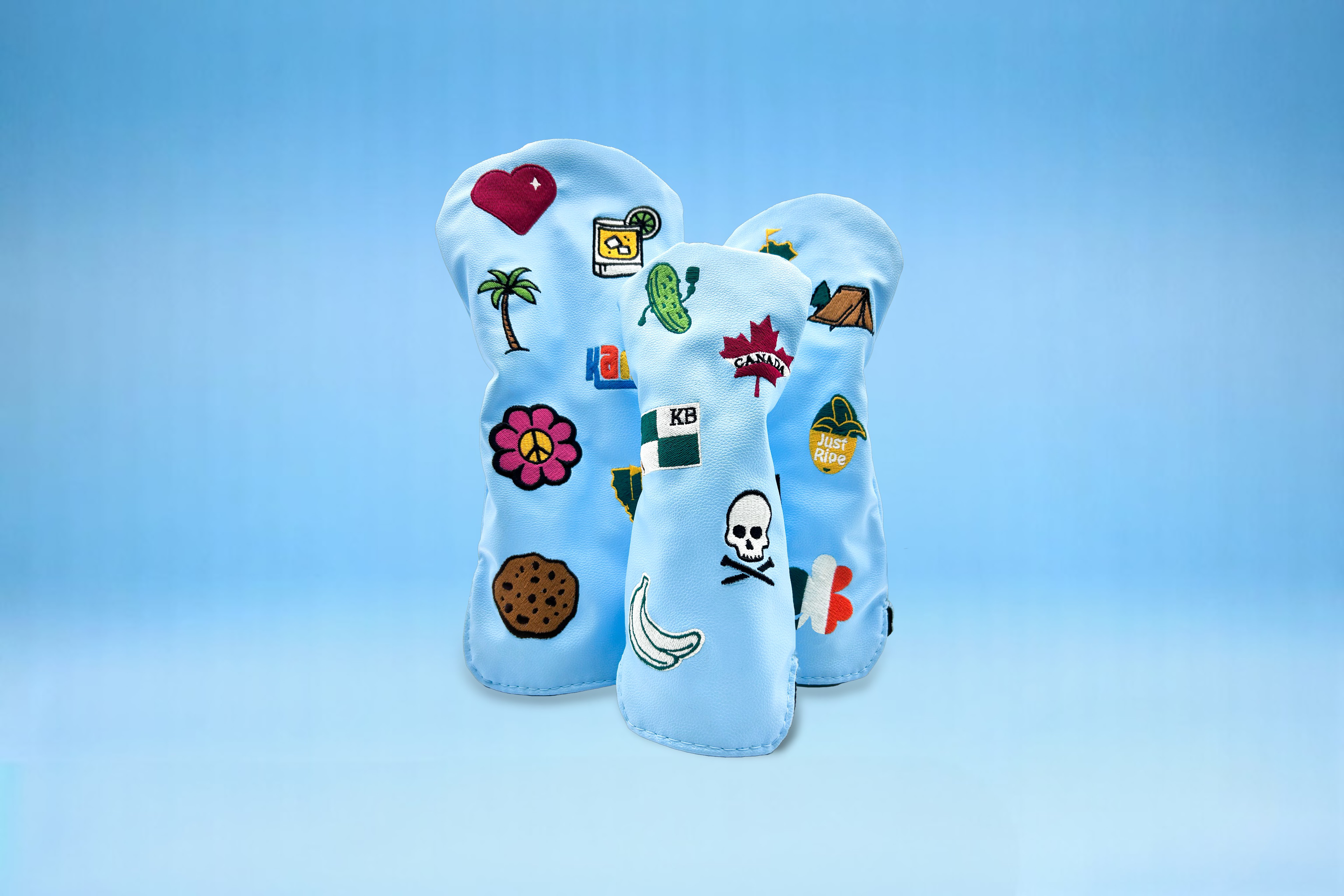 Three blue golf club head covers with custom patches on blue backdrop