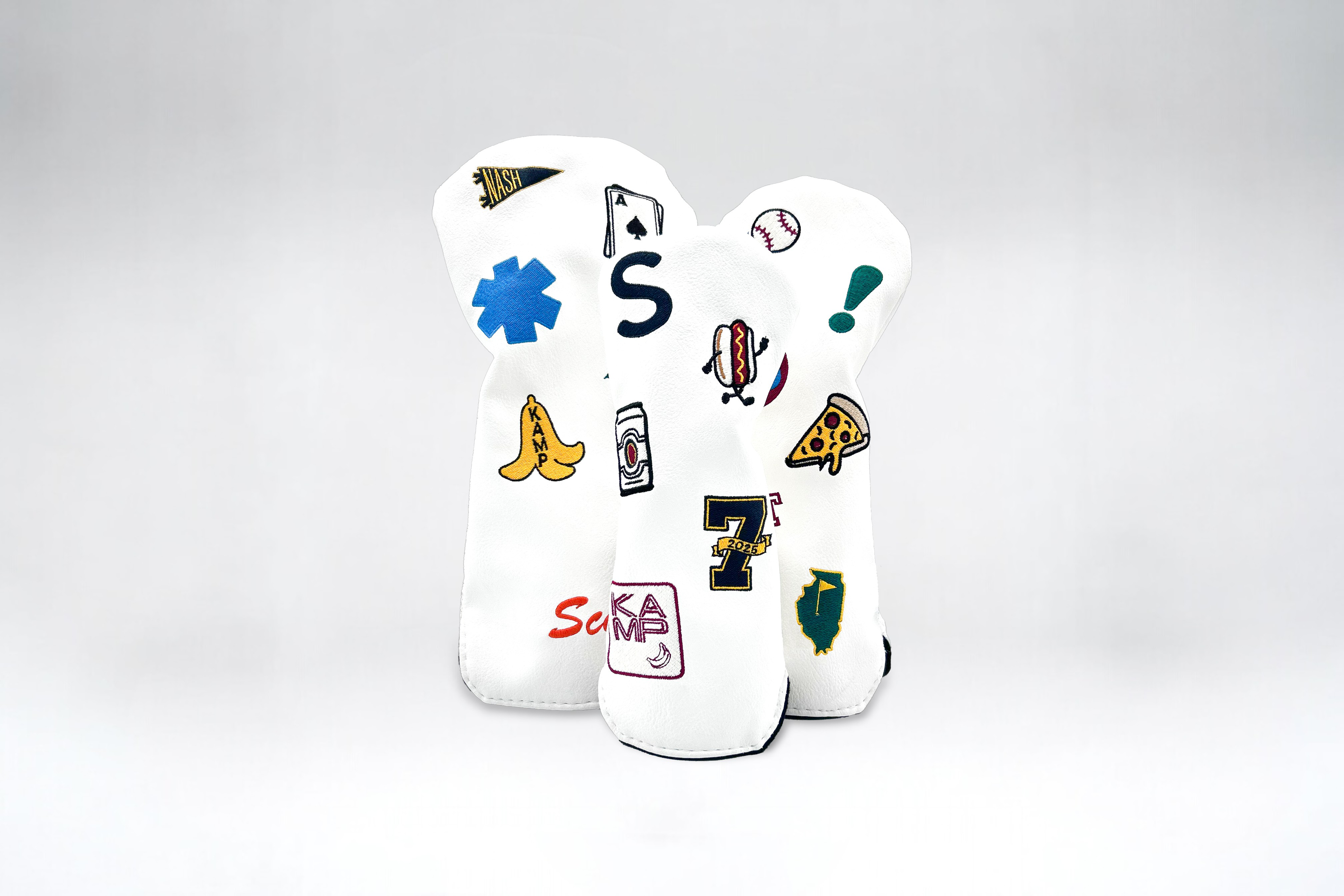 Three white golf club head covers with custom patches on white backdrop